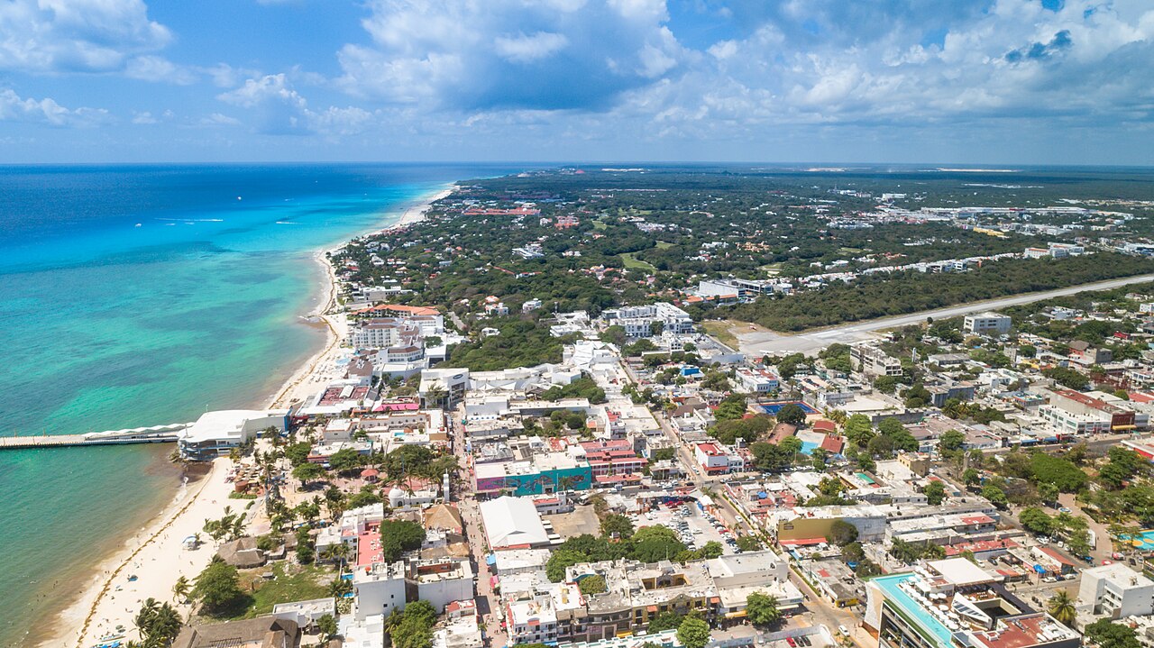 Aerial view of Playa del Carmen showing the pier, the turquoise coast, the town grid and forest inland