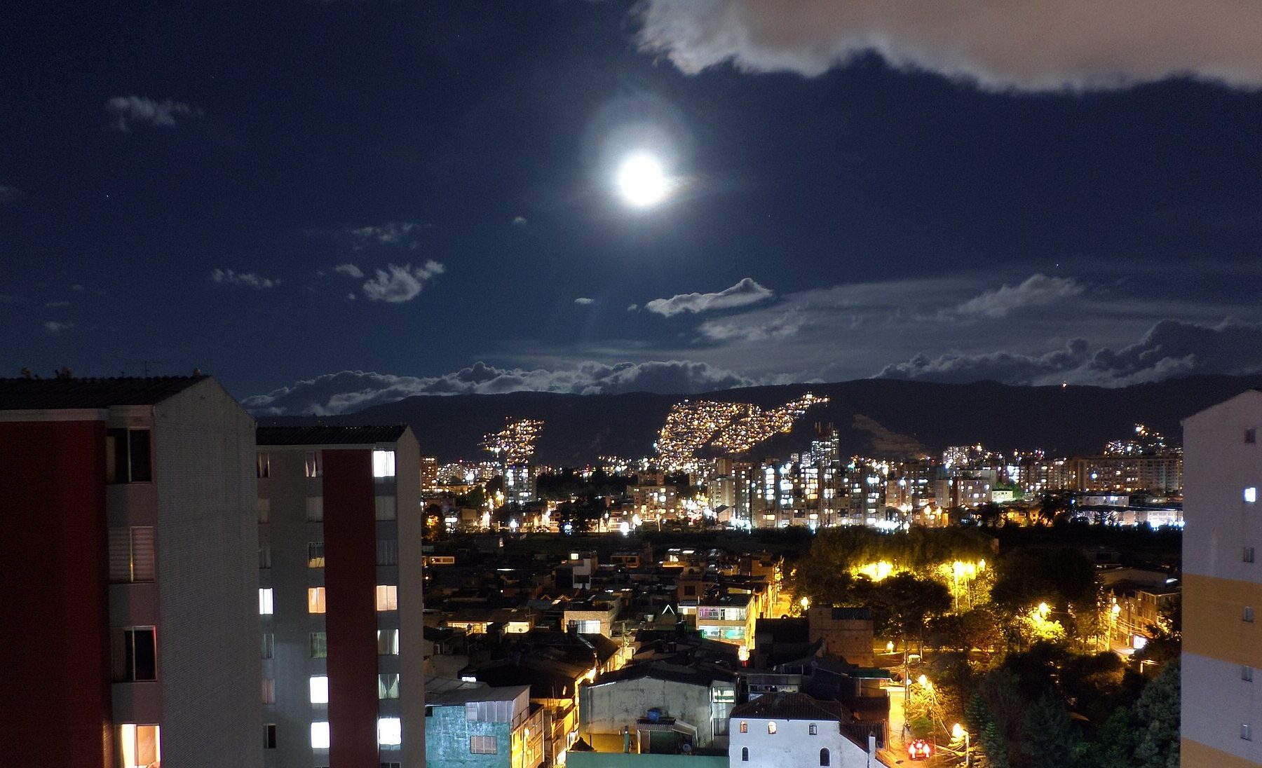 Northern Bogotá at night under a full moon, with the eastern hills behind