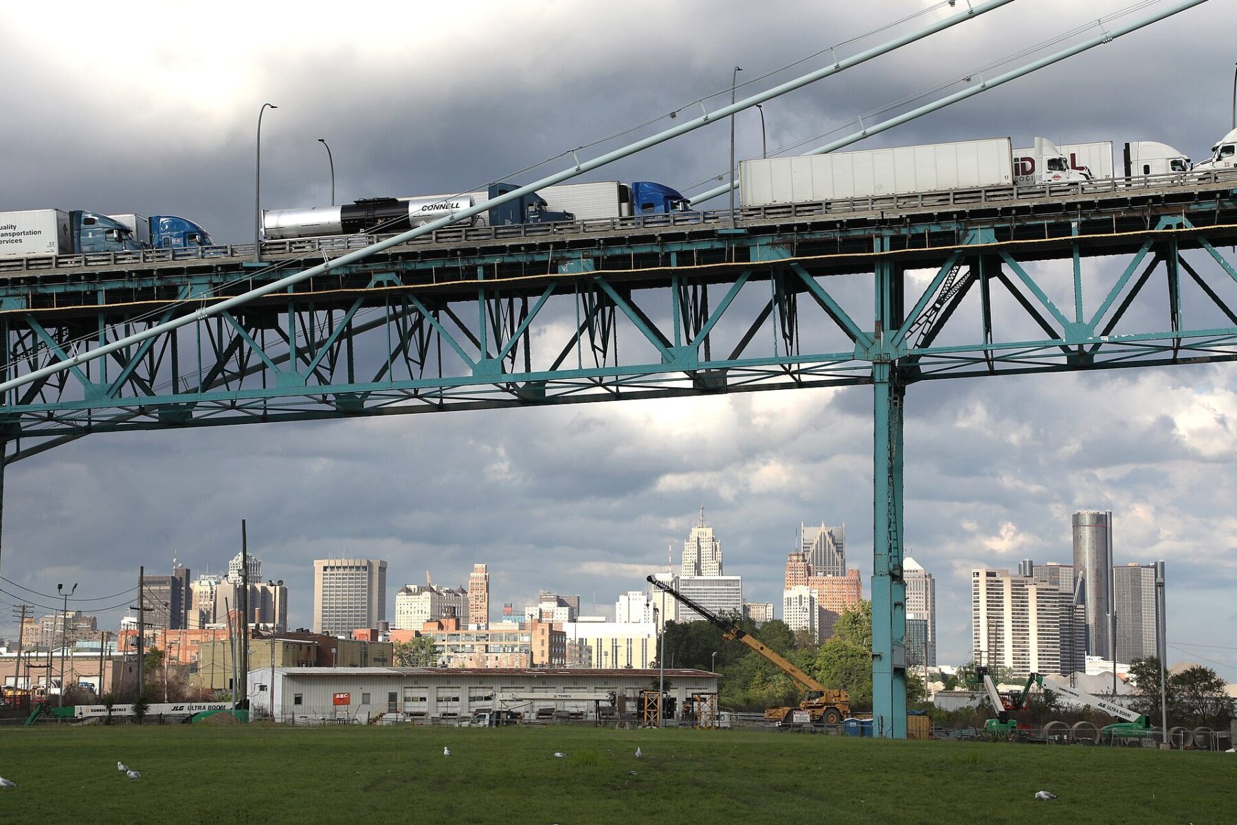 Trucks crossing the Ambassador Bridge with the Detroit skyline below.