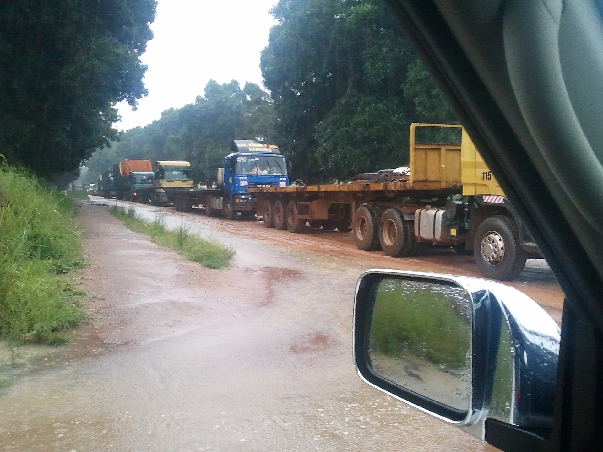 A line of cargo trucks from a Bangui-Douala commercial convoy parked on a red-earth road in Bouar, Central African Republic