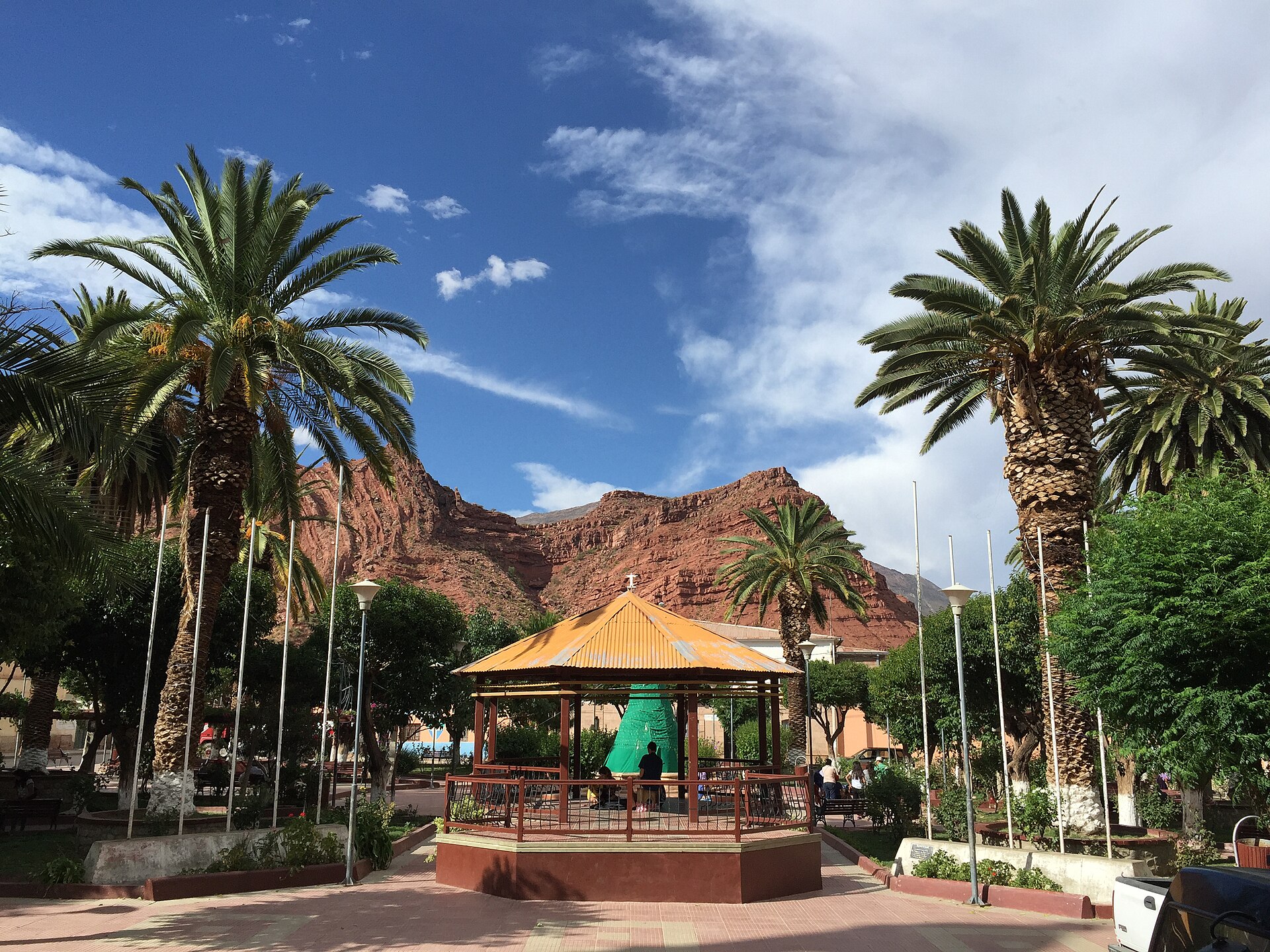 Palm trees and a bandstand in the main square of Camargo, Chuquisaca, Bolivia, with red cliffs behind