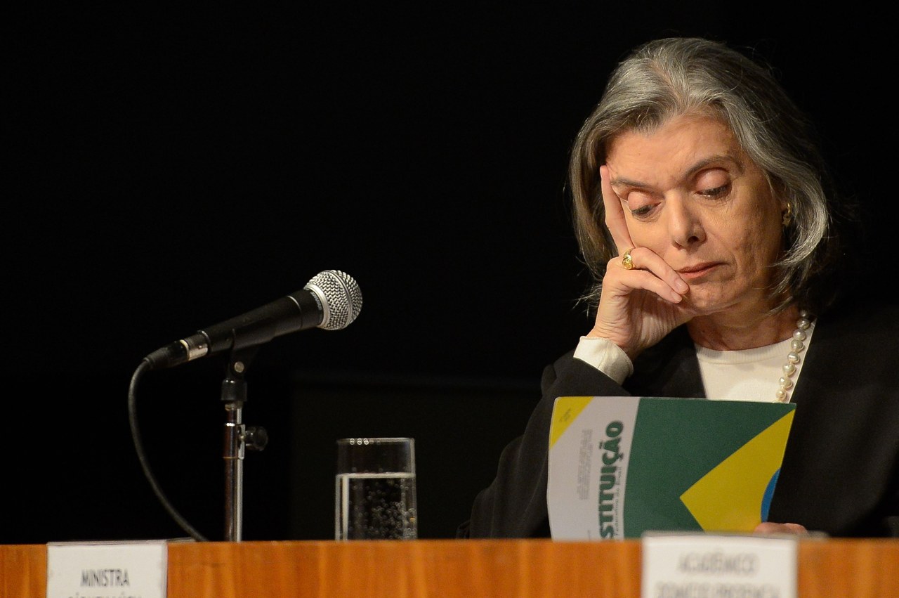 Justice Cármen Lúcia of Brazil's Supreme Court seated at a microphone, resting her face on her hand