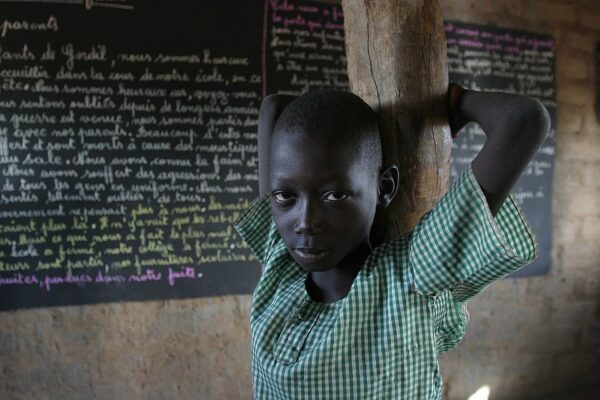 A schoolchild in a green checked shirt stands in a classroom in Gordil, northern Central African Republic, in front of a blackboard covered in French handwriting