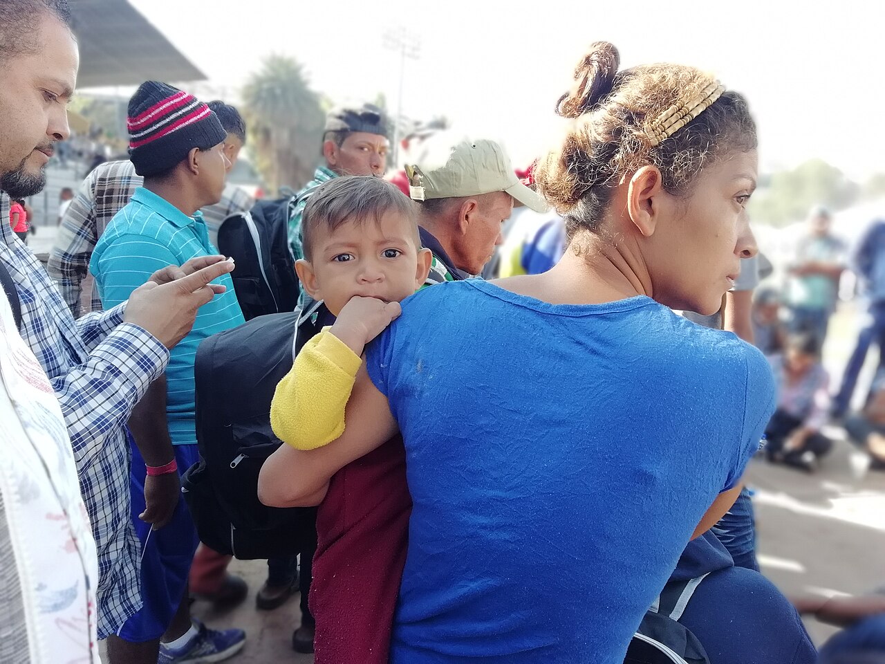 A woman carries a small boy on her back among members of a migrant caravan in Mexico City