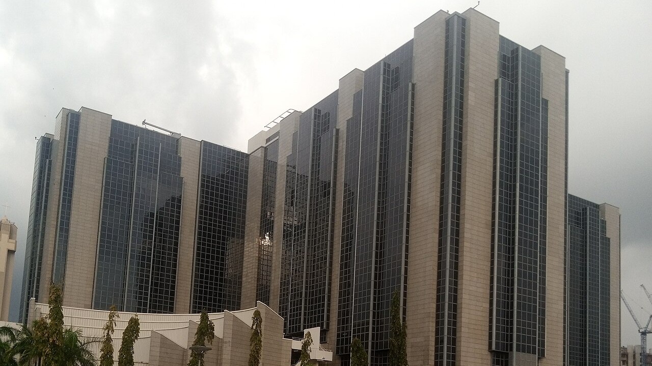 Glass-and-stone headquarters of the Central Bank of Nigeria in Abuja under a cloudy sky