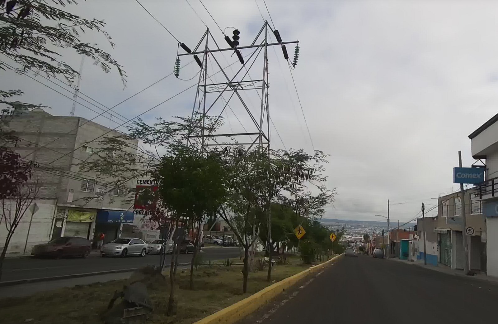 A high-voltage transmission tower beside a street in Querétaro, Mexico