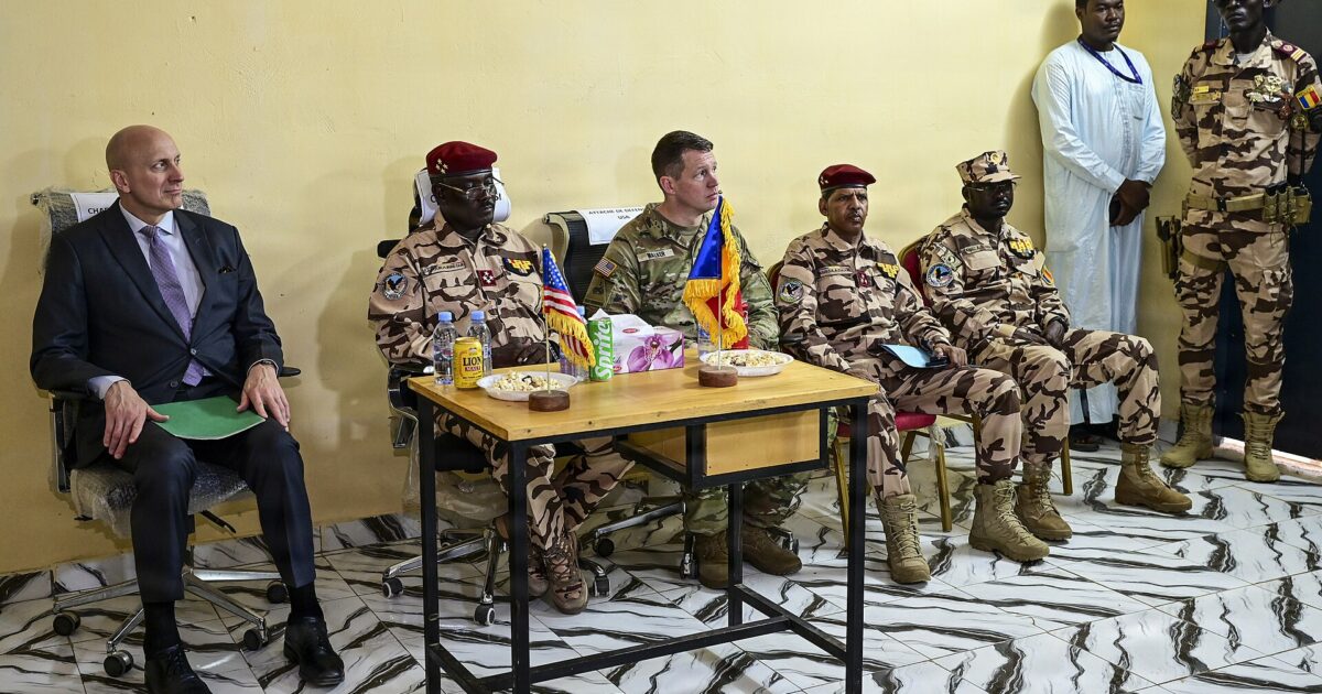 Chadian army officers and US officials seated at a table with small Chadian and US flags during a ceremony in N'Djamena
