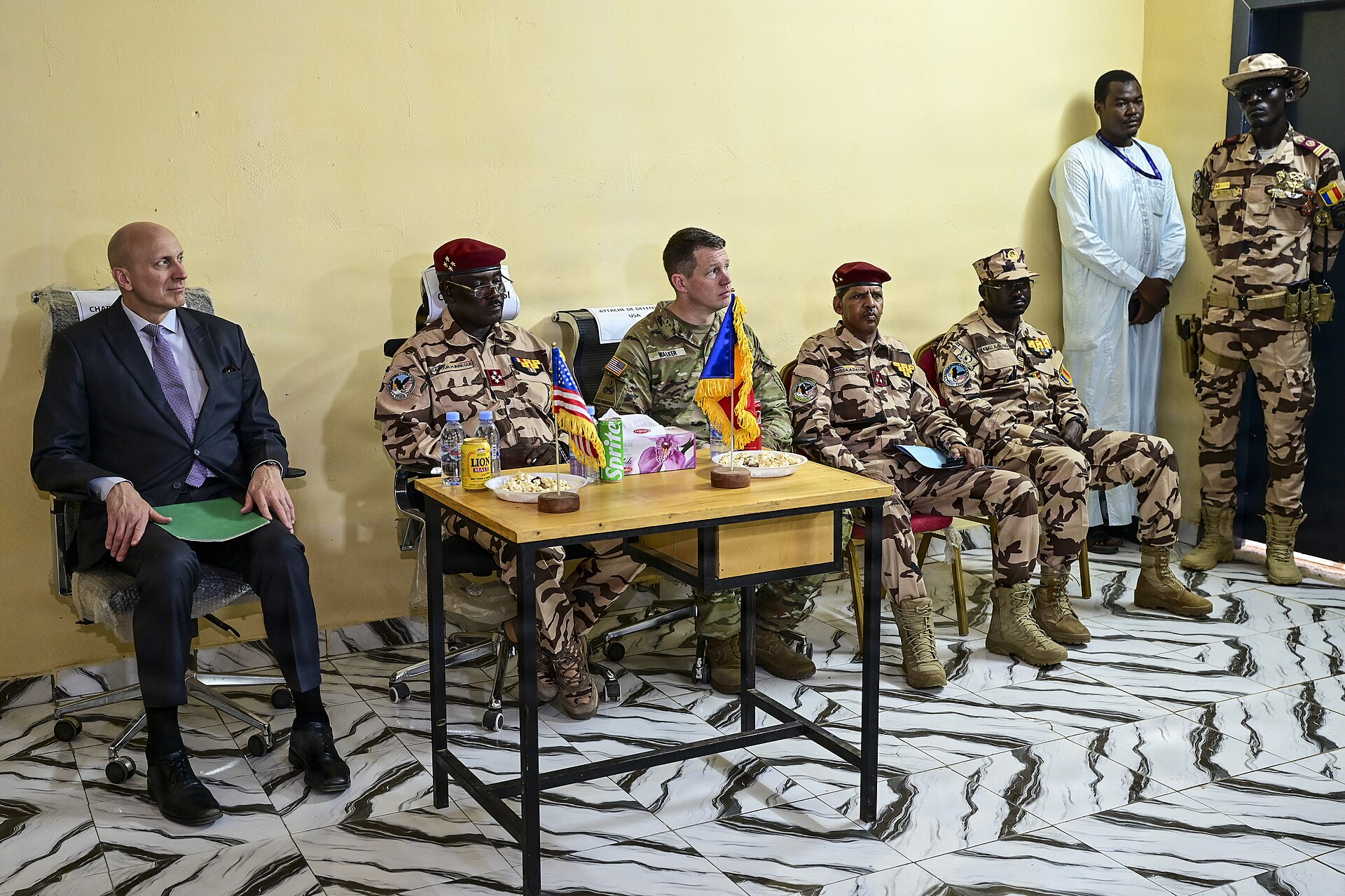 Chadian army officers and US officials seated at a table with small Chadian and US flags during a ceremony in N'Djamena
