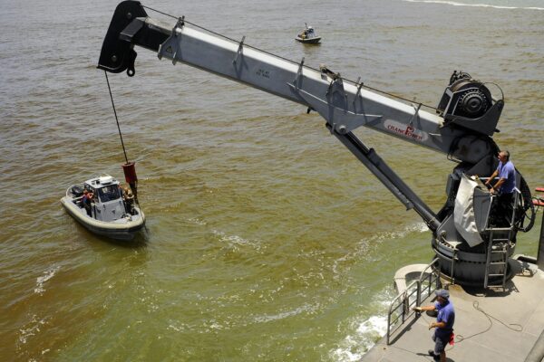 Contractor mariners lower a survey boat into the water in Georgetown, Guyana, to measure the depth of the port
