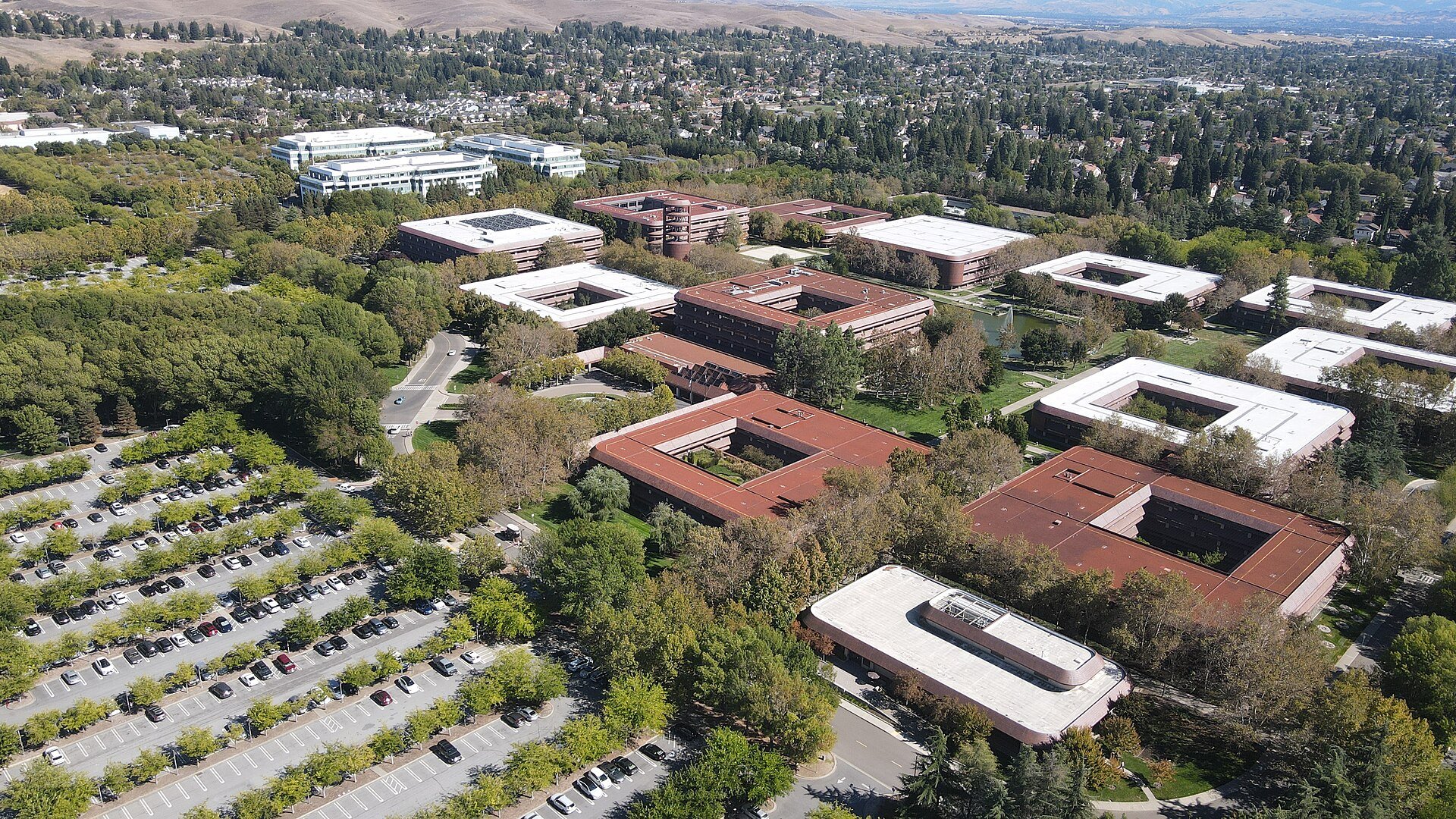 Aerial view of a large office campus with low buildings, parking lots and green hills in San Ramon, California