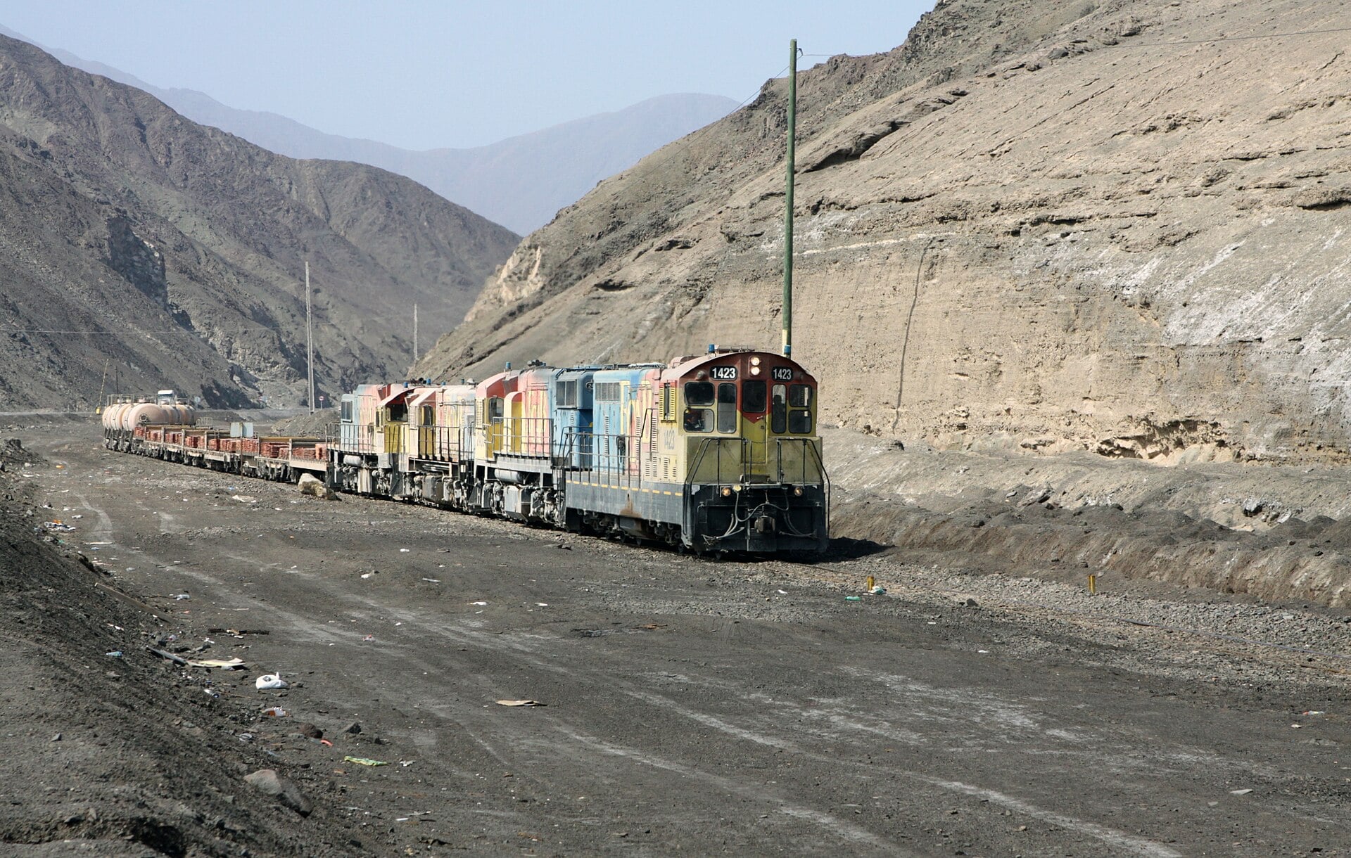 A freight train carries stacked copper plates through a desert valley in northern Chile