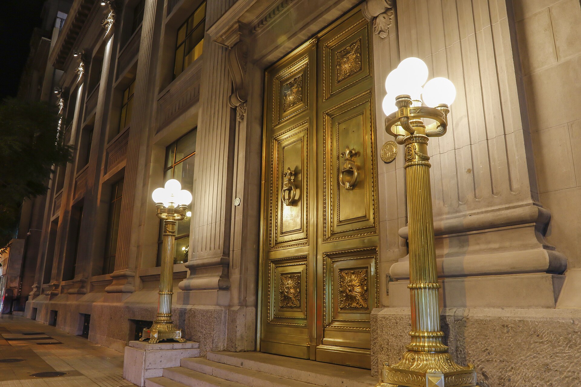 Bronze doors and street lamps at the entrance of the Banco Central de Chile building in Santiago at night