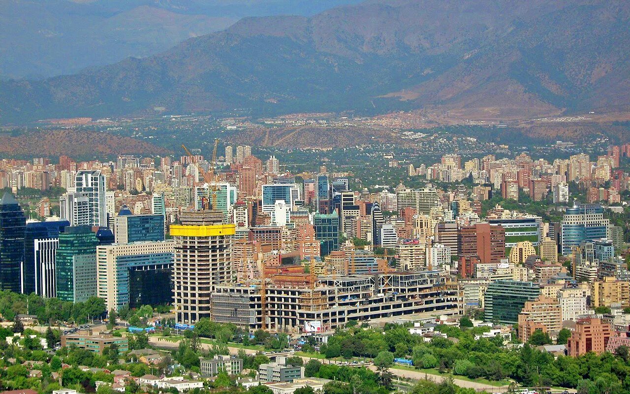 Office towers and apartment blocks of Santiago's business districts below the Andes foothills, with a tower under construction