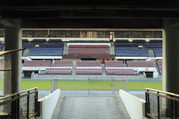 Red and blue seating stands of the Estadio Nacional in Santiago, Chile, seen from a tunnel entrance onto the pitch