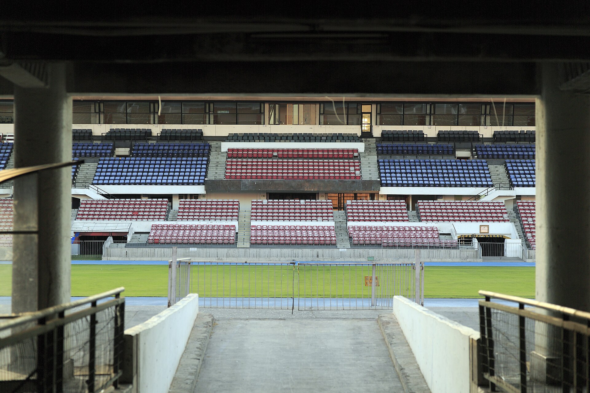 Red and blue seating stands of the Estadio Nacional in Santiago, Chile, seen from a tunnel entrance onto the pitch