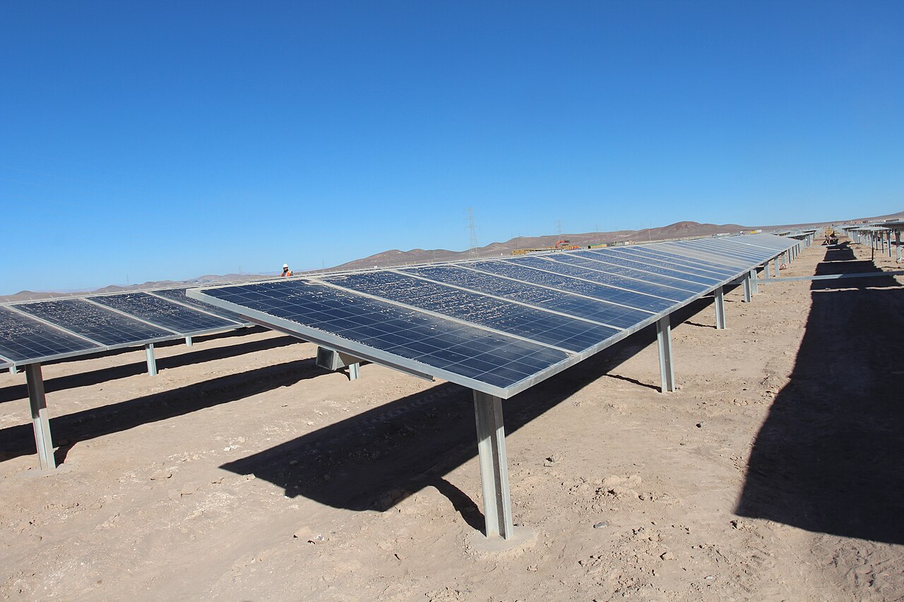 Rows of solar panels at a solar plant in northern Chile under a clear blue sky