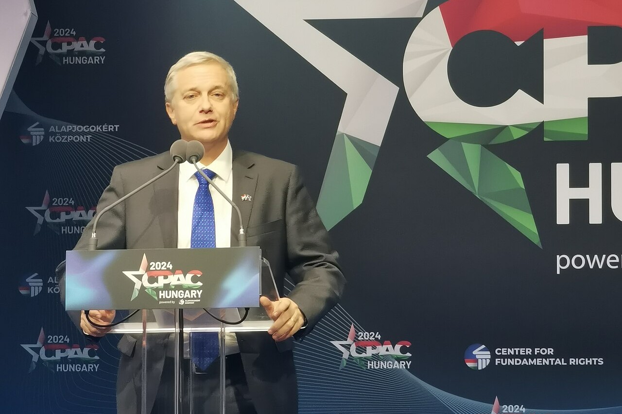 José Antonio Kast in a grey suit and blue tie speaking at a lectern in front of a CPAC Hungary 2024 backdrop