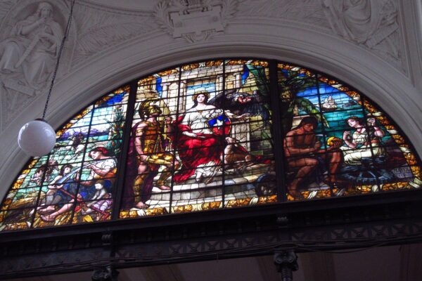 A stained-glass window in the Palace of Courts in Santiago showing an allegory of justice, with a seated woman holding a shield in Chile's colors beside a figure with scales
