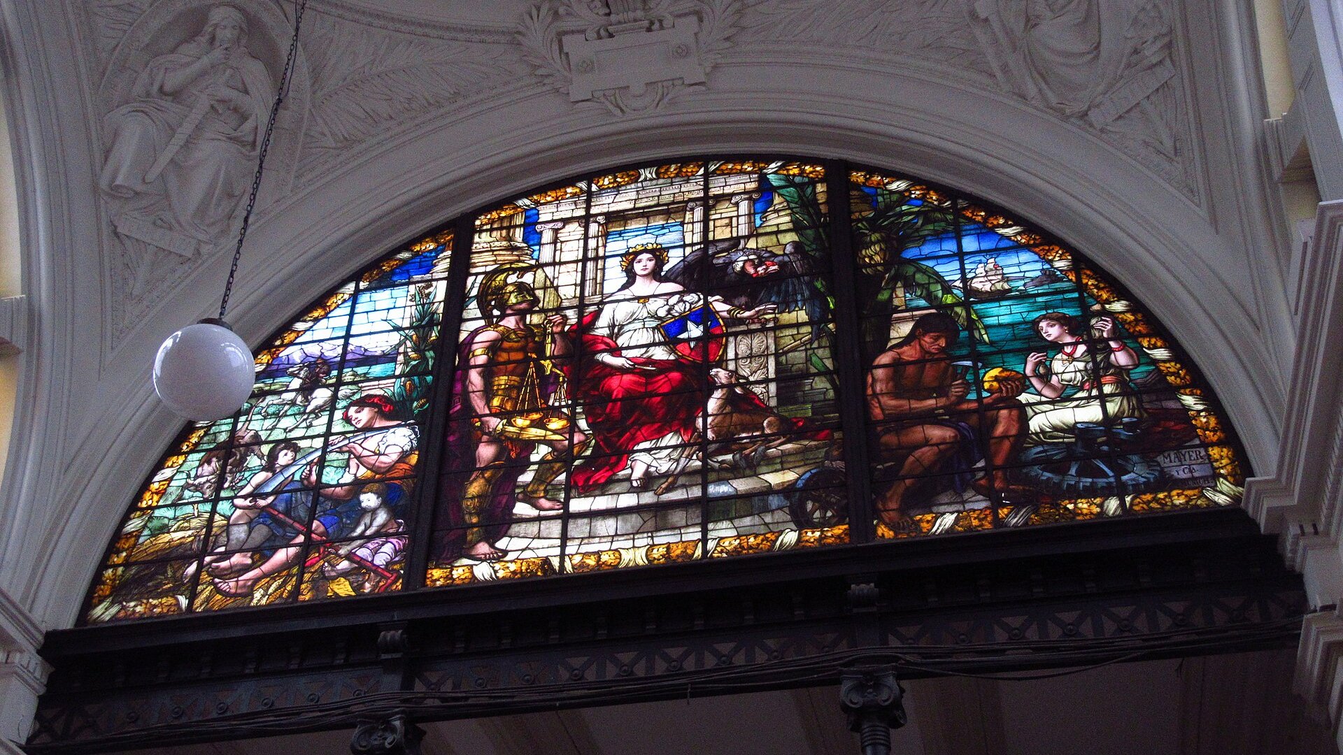 A stained-glass window in the Palace of Courts in Santiago showing an allegory of justice, with a seated woman holding a shield in Chile's colors beside a figure with scales