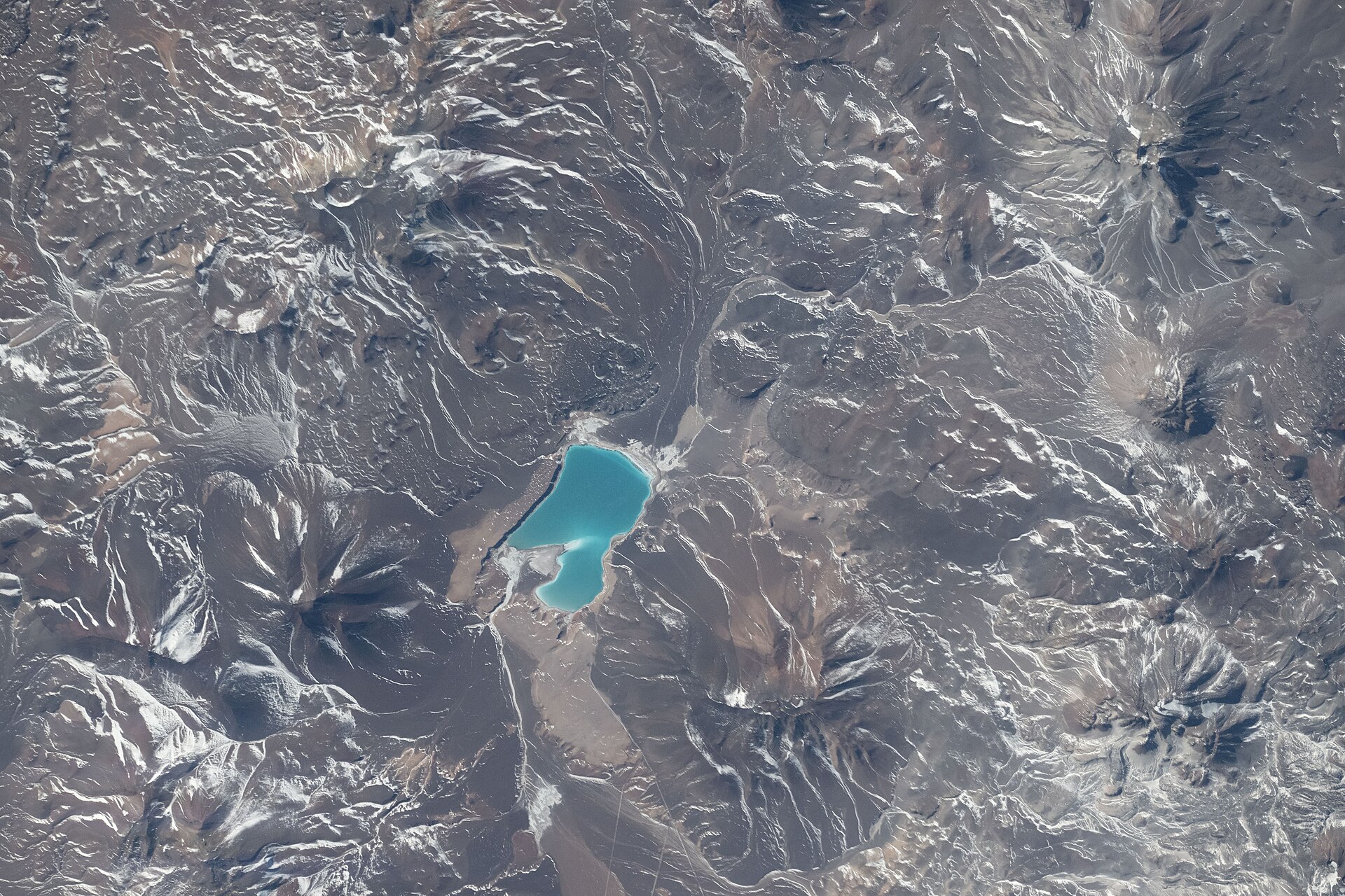 Turquoise high-altitude lake Laguna Verde among brown and snow-streaked mountains of the Andes in northern Chile, seen from the International Space Station in July 2026