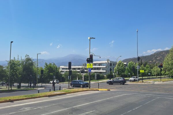 Street intersection with traffic lights in San Carlos de Apoquindo, Las Condes, with the Andes foothills rising behind apartment blocks