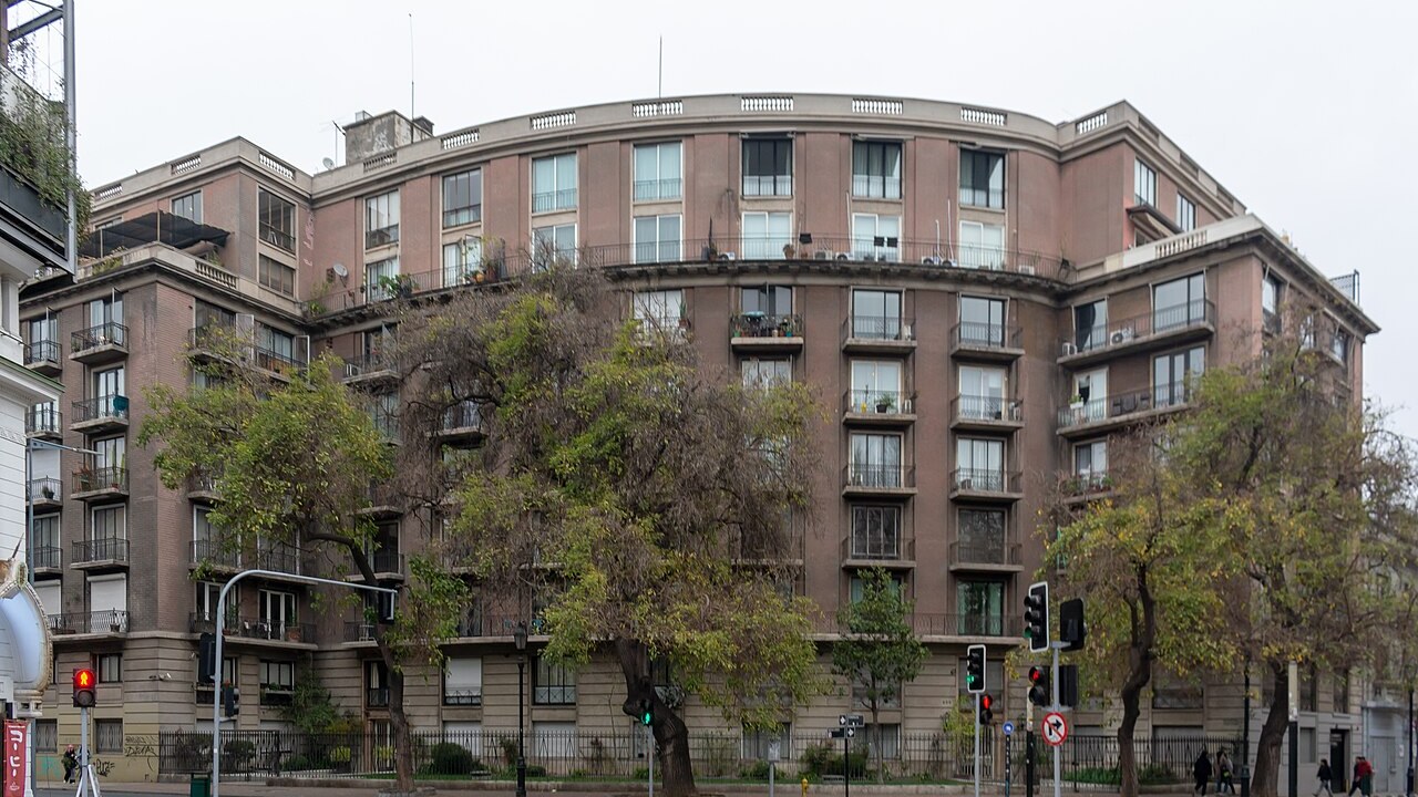 An eight-storey apartment building with balconies on a street corner in central Santiago, Chile