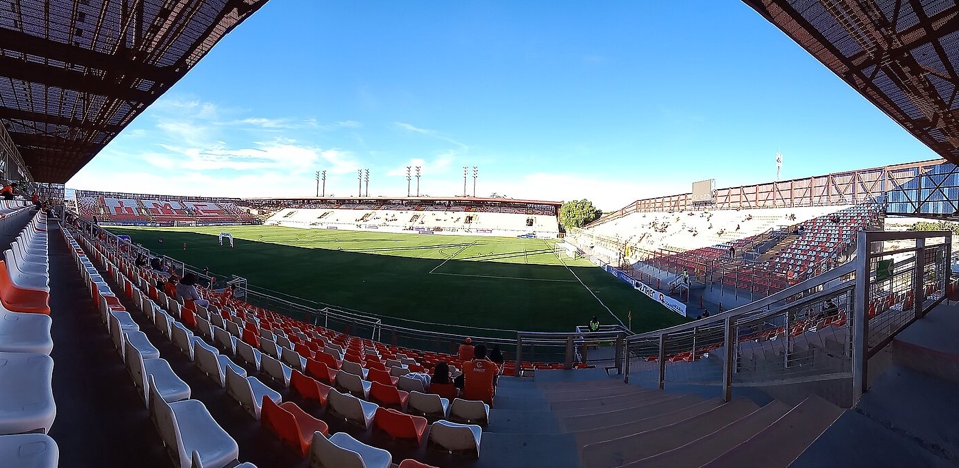 Interior of the Estadio Zorros del Desierto in Calama, Chile, a football stadium with orange and white seats facing the pitch