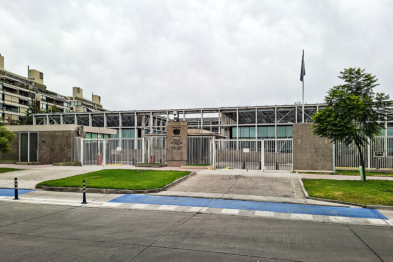 The gated entrance of the ECLAC headquarters in Vitacura, Santiago, with a stone marker bearing the CEPAL name and a flagpole behind it