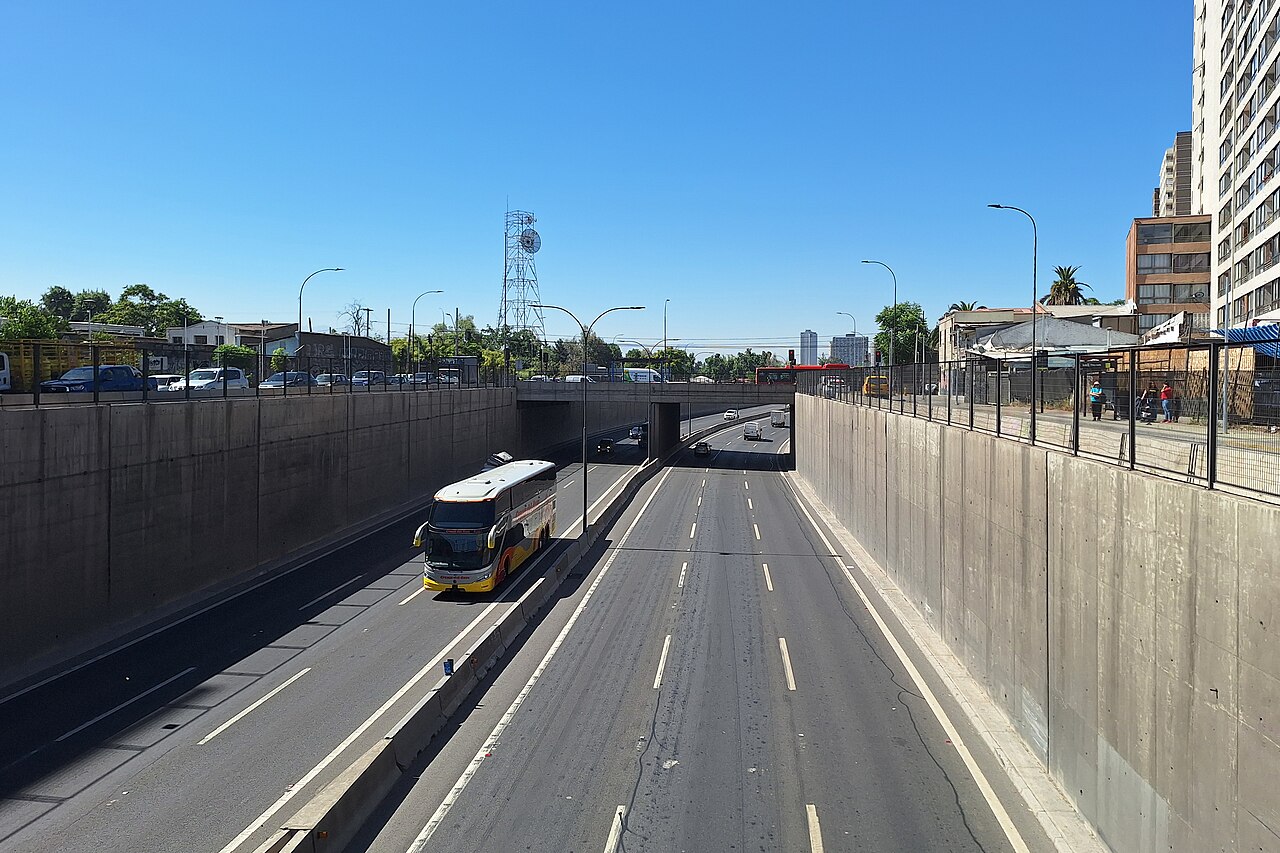 A coach and cars on the sunken lanes of Autopista Central between concrete walls in Quinta Normal, Santiago
