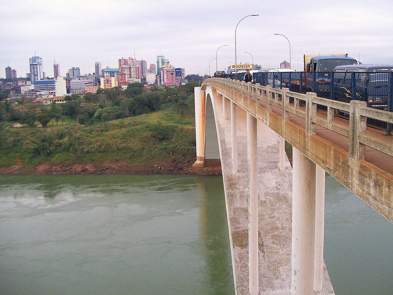 The Friendship Bridge crossing the Paraná River with the Ciudad del Este skyline in the distance and trucks on the bridge deck