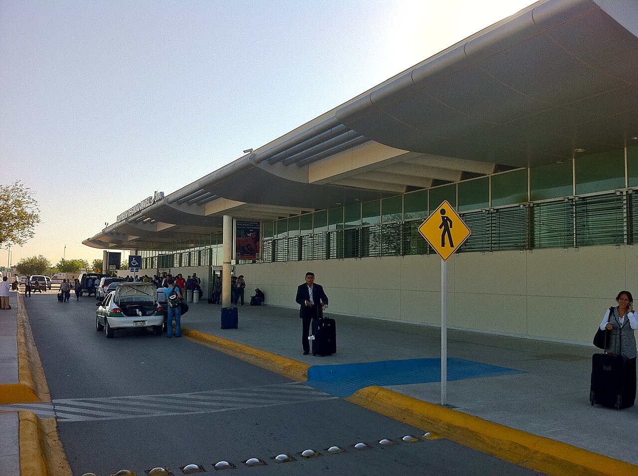 Terminal building of Ciudad Juárez International Airport with travellers and luggage at the curb