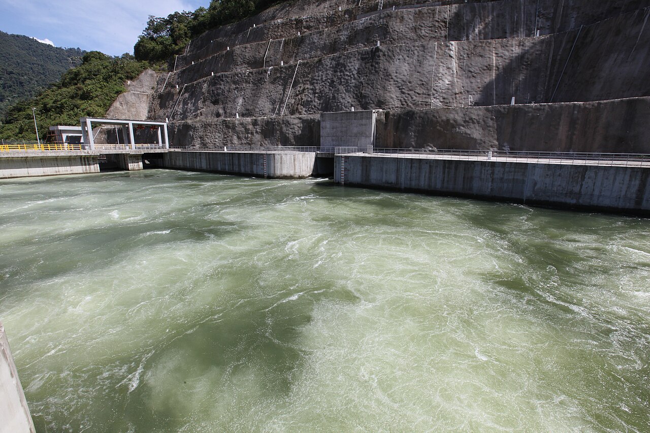 Green, fast-flowing river water in a concrete basin below a terraced rock wall at the Coca Codo Sinclair plant in Ecuador