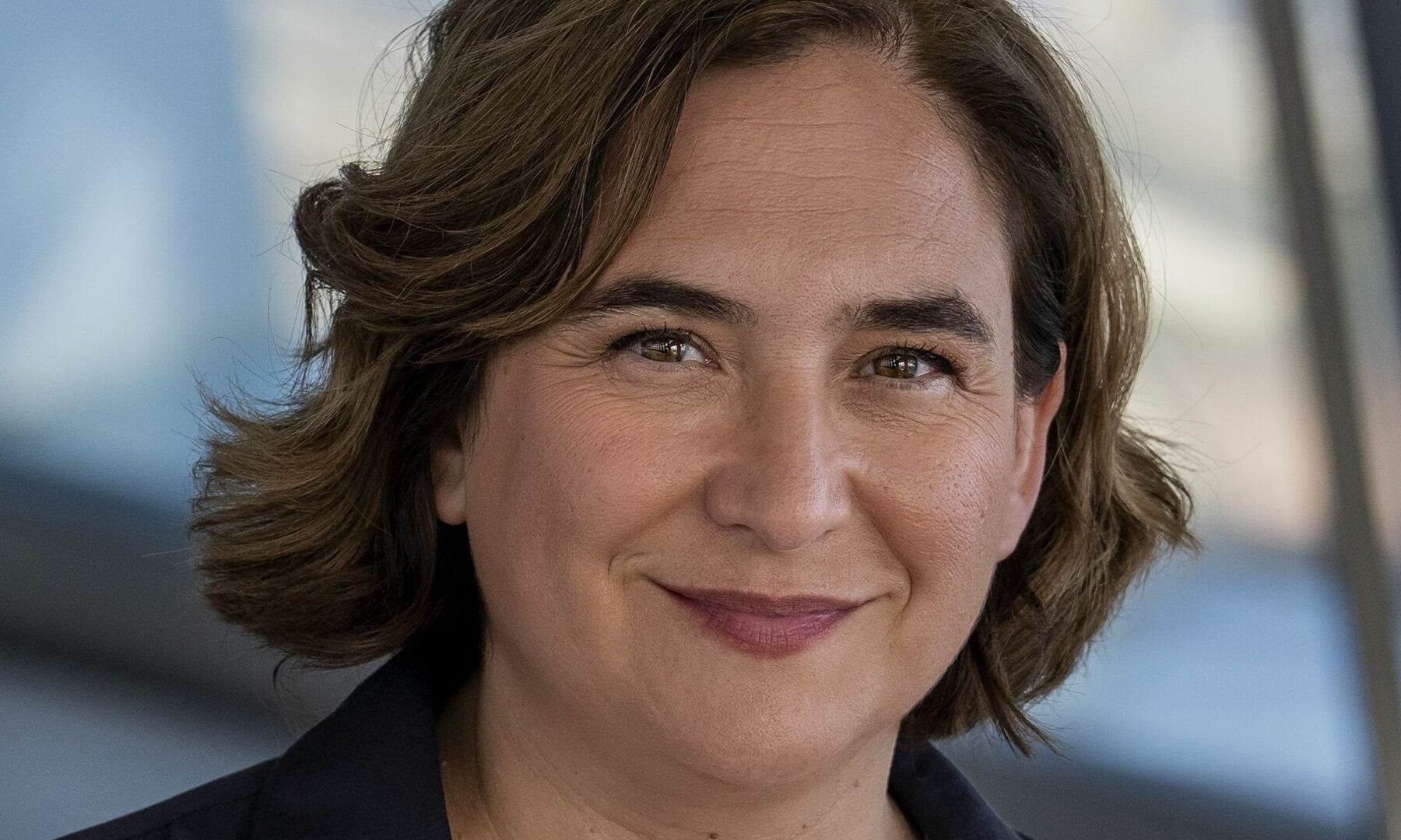 Ada Colau, leader of Spain's Frente Amplio alliance, smiling in a dark jacket
