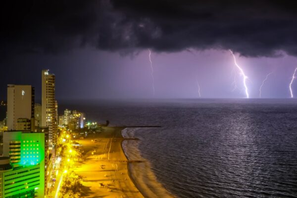 Lightning bolts over the Caribbean Sea beside the high-rise skyline and beach of Cartagena, Colombia, at night