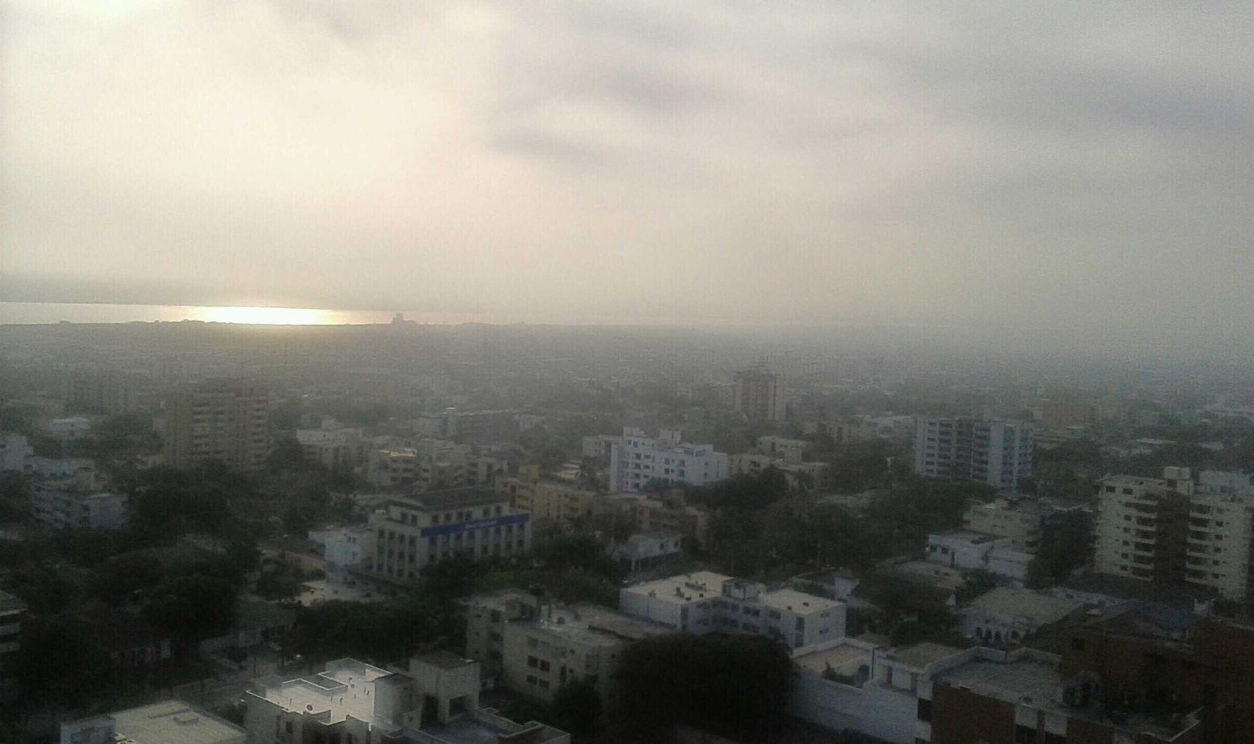 Hazy view over low buildings in Barranquilla, Colombia, with water on the horizon