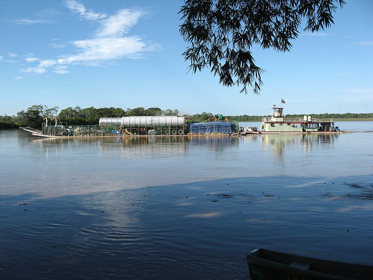 A river ferry pushing a cargo barge with tanker trailers across the wide Meta River in eastern Colombia