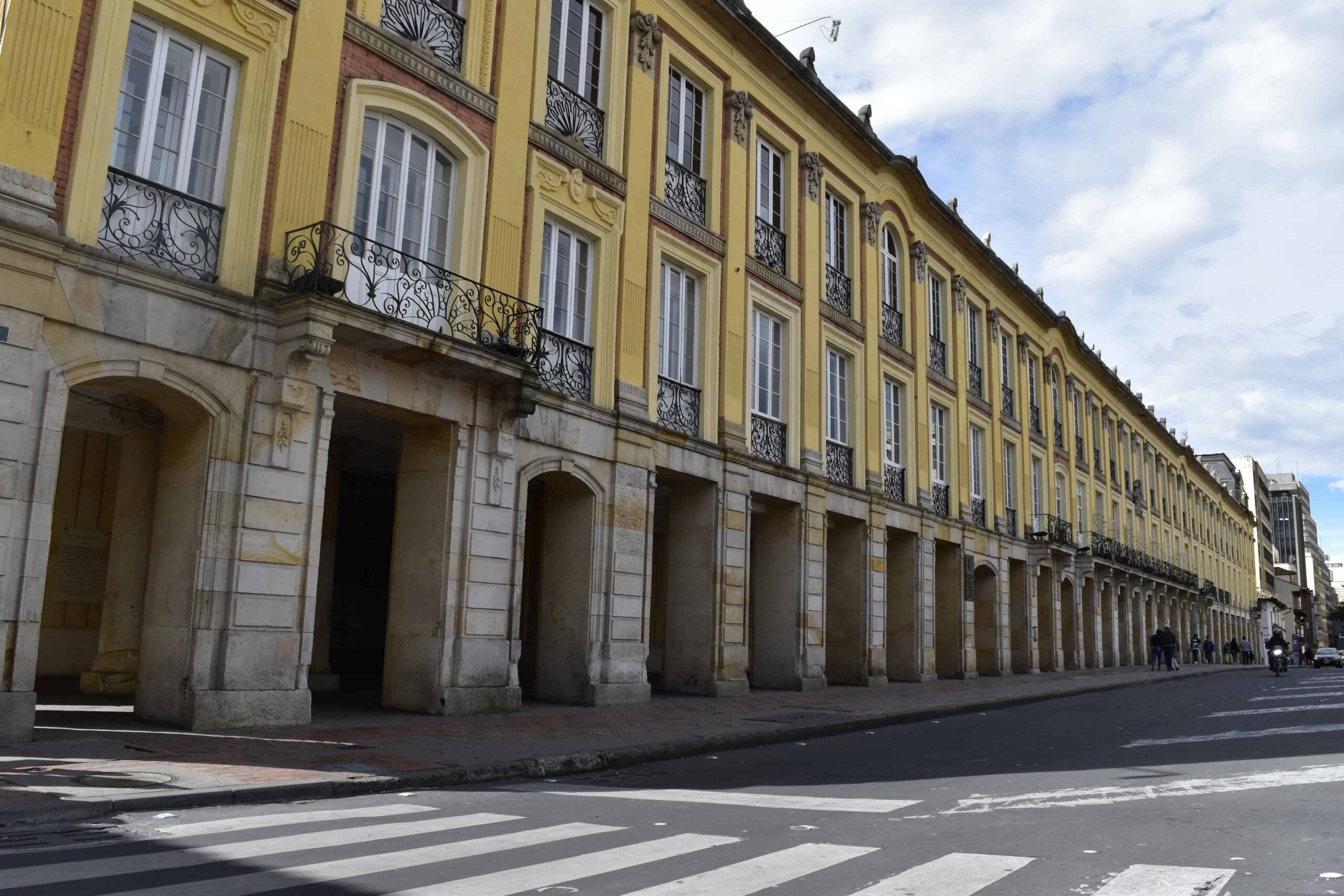 Yellow colonial building with iron balconies and an arcade along a street in central Bogotá