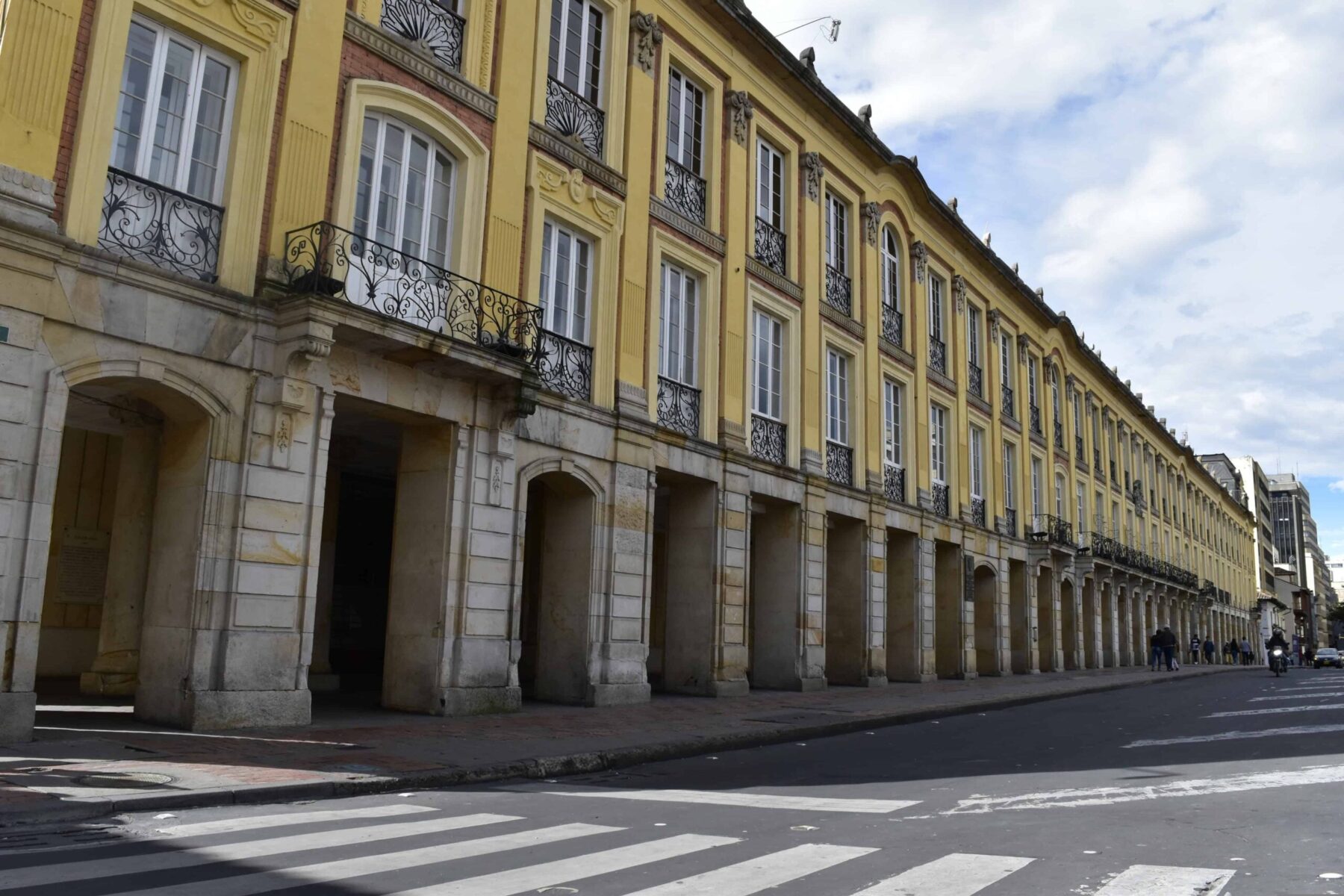 Yellow colonial-style arcaded building with iron balconies on a street in central Bogotá, Colombia
