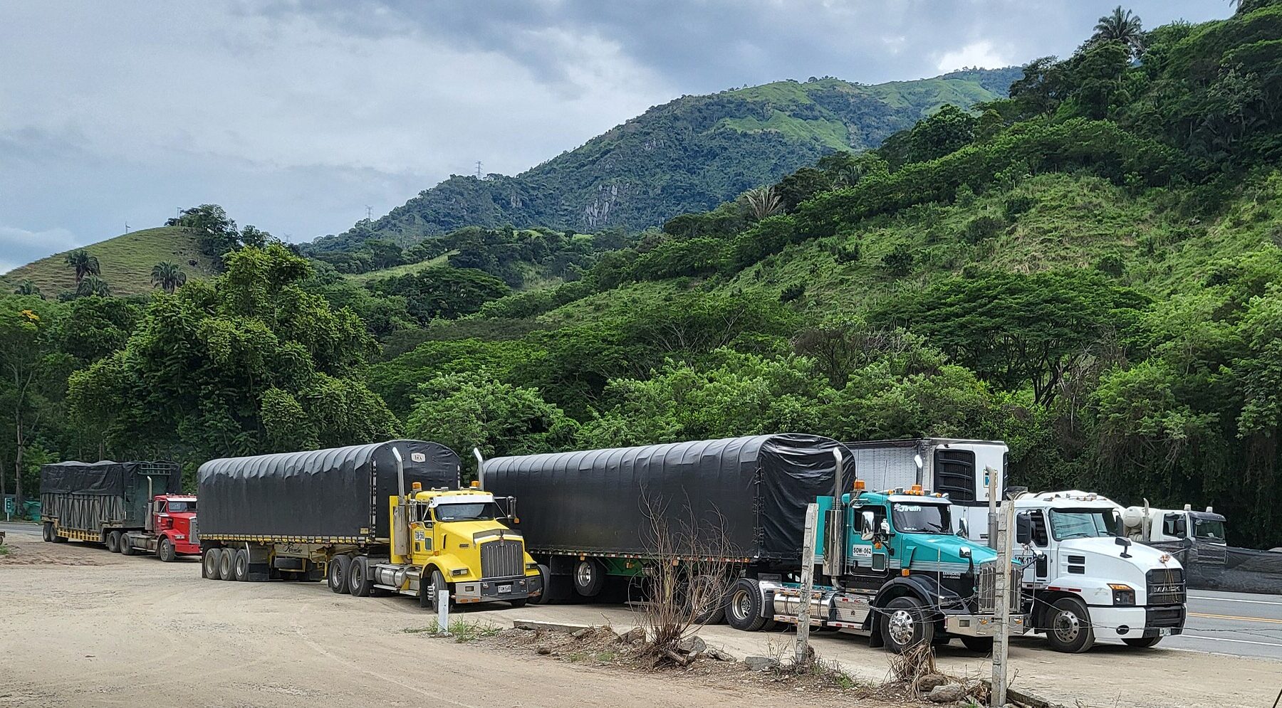 Articulated diesel lorries parked beside a road in the green hills of Antioquia, Colombia
