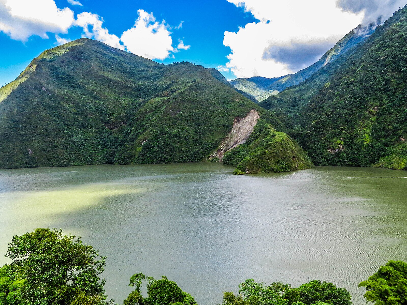 The Chivor reservoir in the Andes of Boyacá, Colombia, with forested mountains and a blue sky