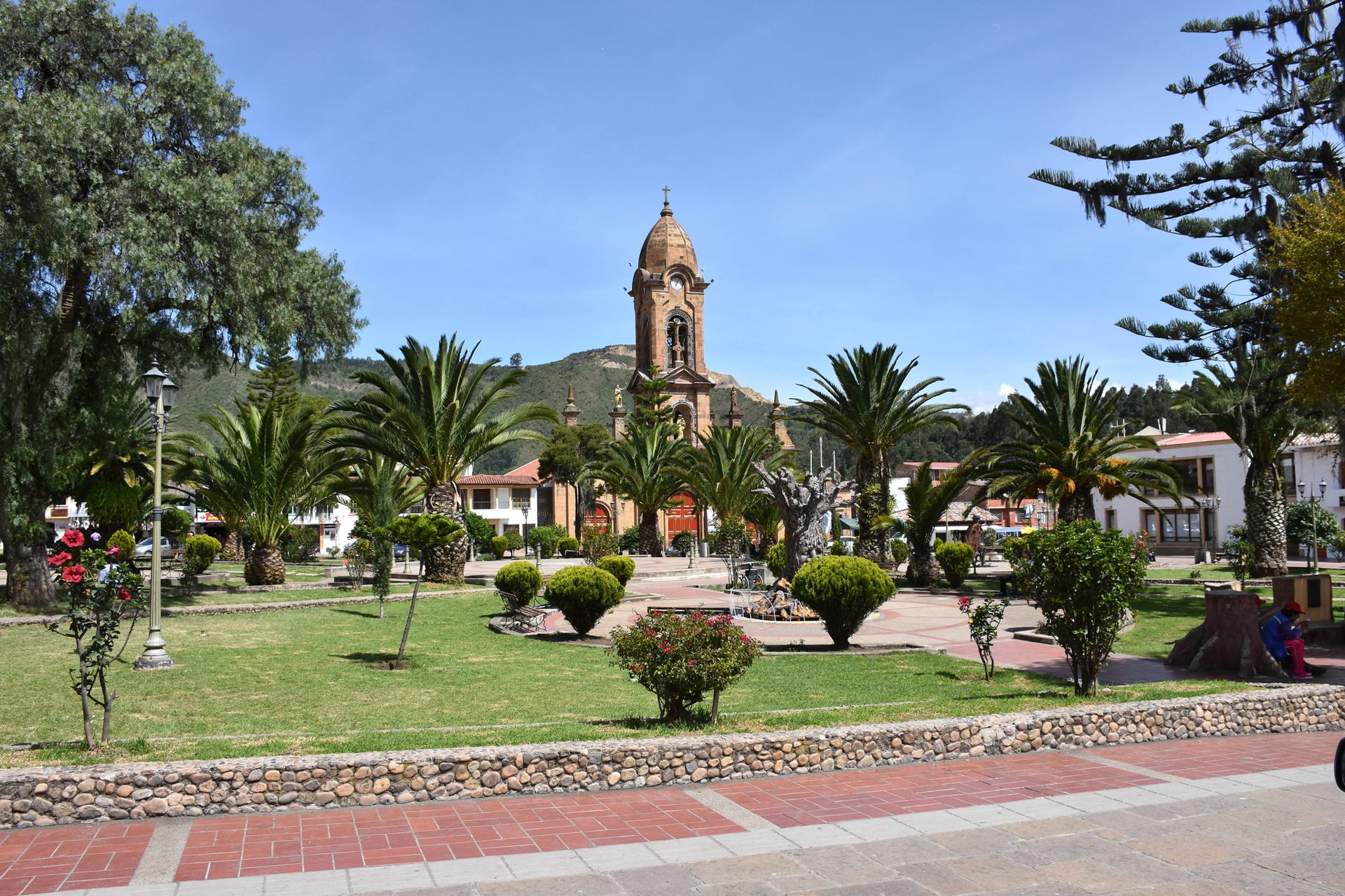 The main square of Nobsa in Boyacá, Colombia, with its church tower, palm trees and green hills behind
