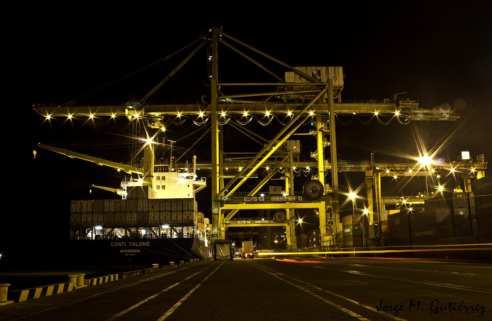 Lit container gantry cranes and a ship at night at the Buenaventura port terminal on Colombia's Pacific coast
