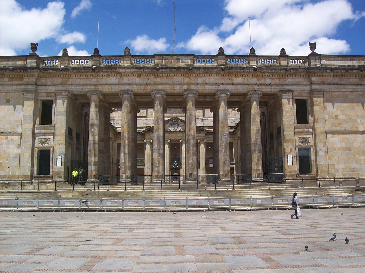 Stone colonnade of the Capitolio Nacional facing a paved square in Bogotá under a blue sky