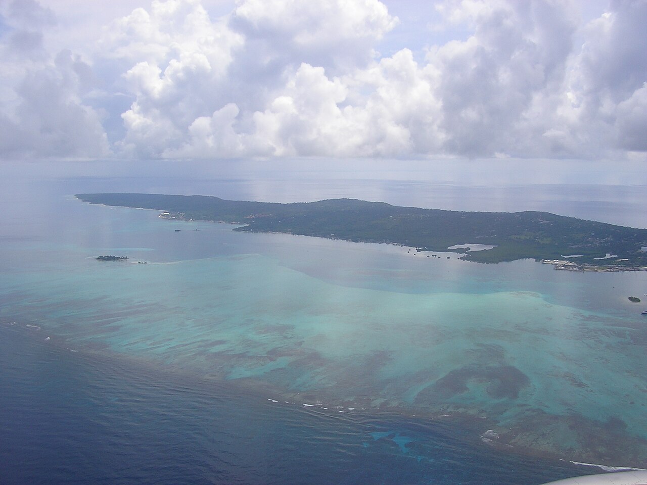 Aerial view of San Andrés island in the Caribbean, with green hills, turquoise reef shallows and clouds over the sea