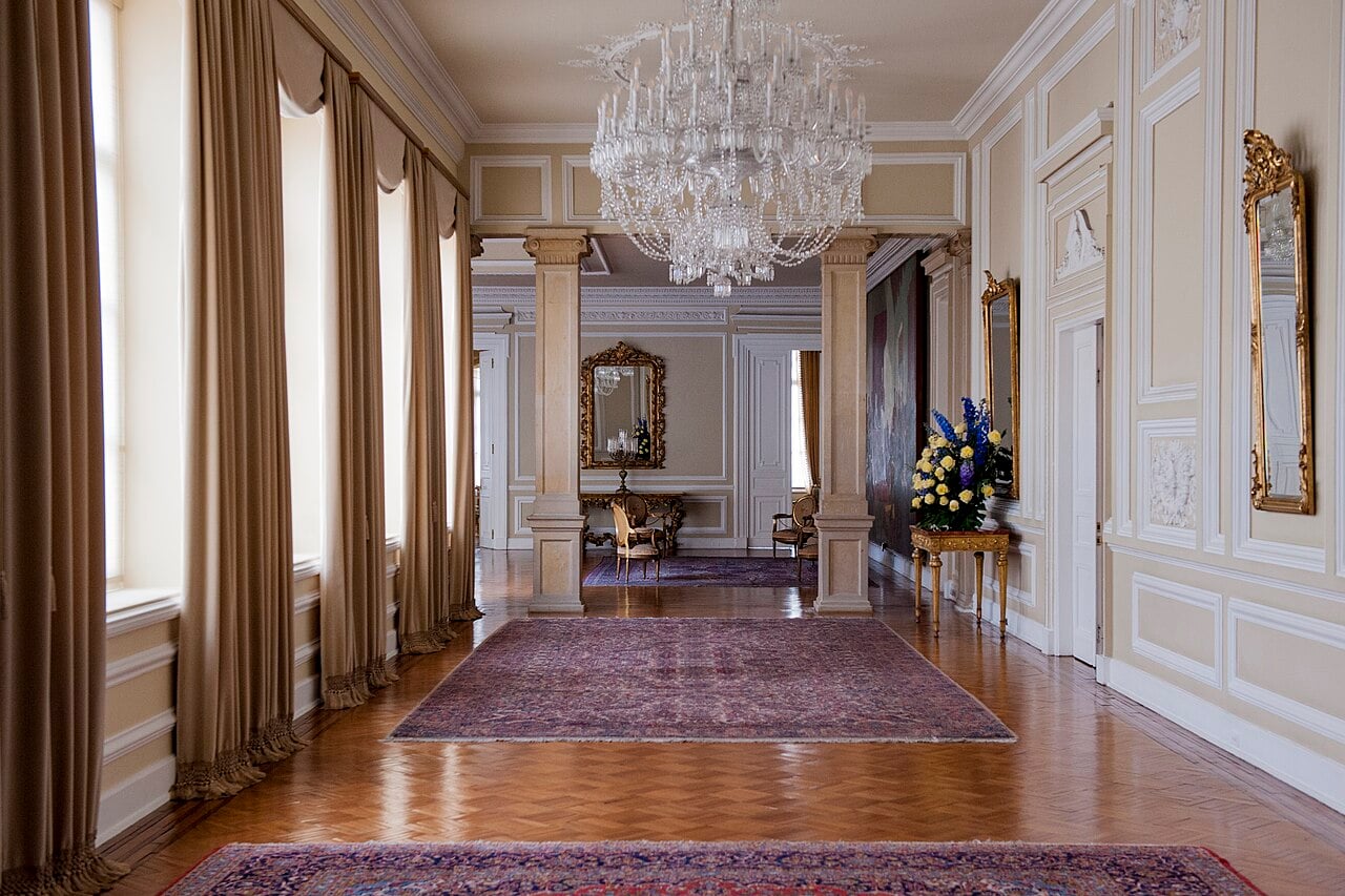 Long reception hall with a crystal chandelier, columns, mirrors and rugs inside the Casa de Nariño presidential palace in Bogotá