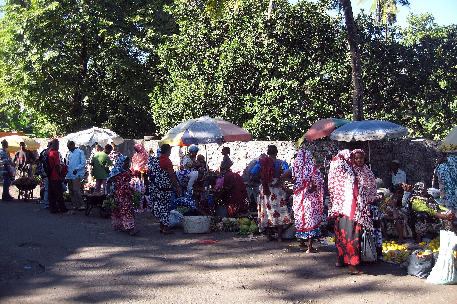 Women in colourful wraps sell fruit and vegetables under umbrellas at the old market in Moroni, Comoros