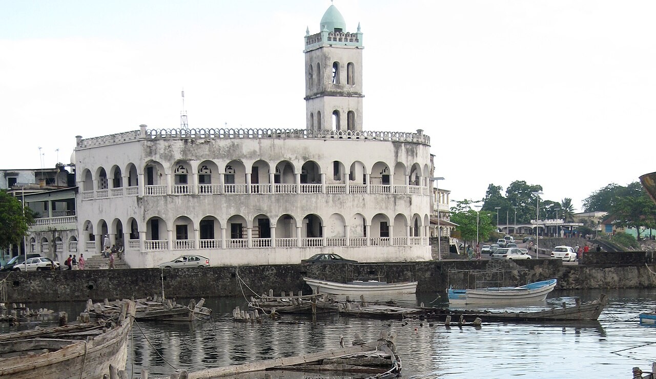 The Old Friday Mosque, a white colonnaded building with a square tower, above the harbour of Moroni, Comoros
