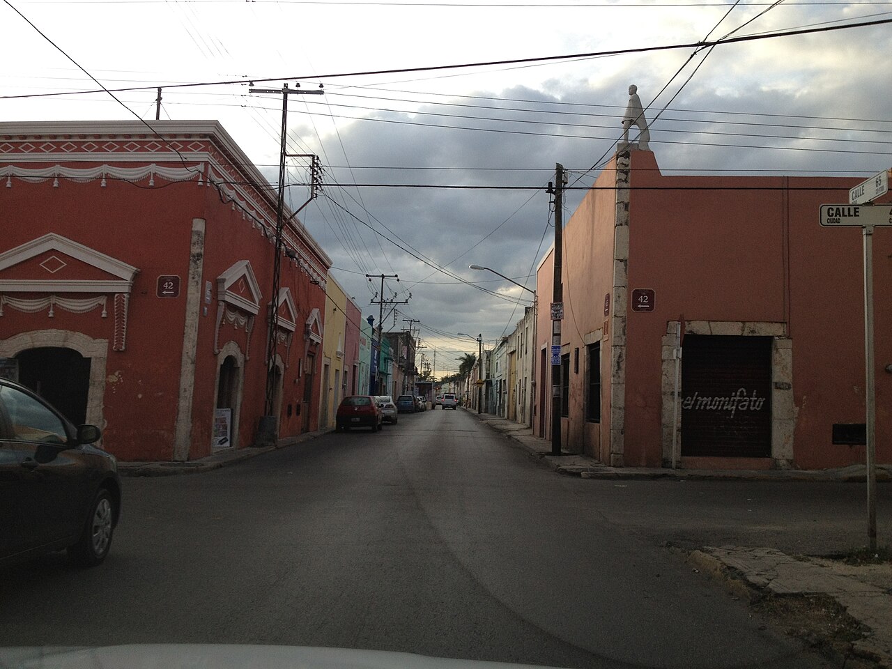 Street in the historic centre of Mérida, Yucatán, with colourful single-storey buildings, parked cars and power lines