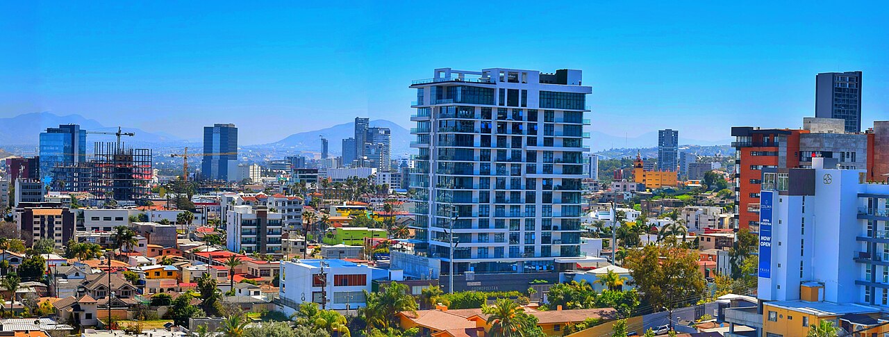 Skyline of Tijuana, Mexico, with apartment towers, low-rise homes, construction cranes and hills in the distance