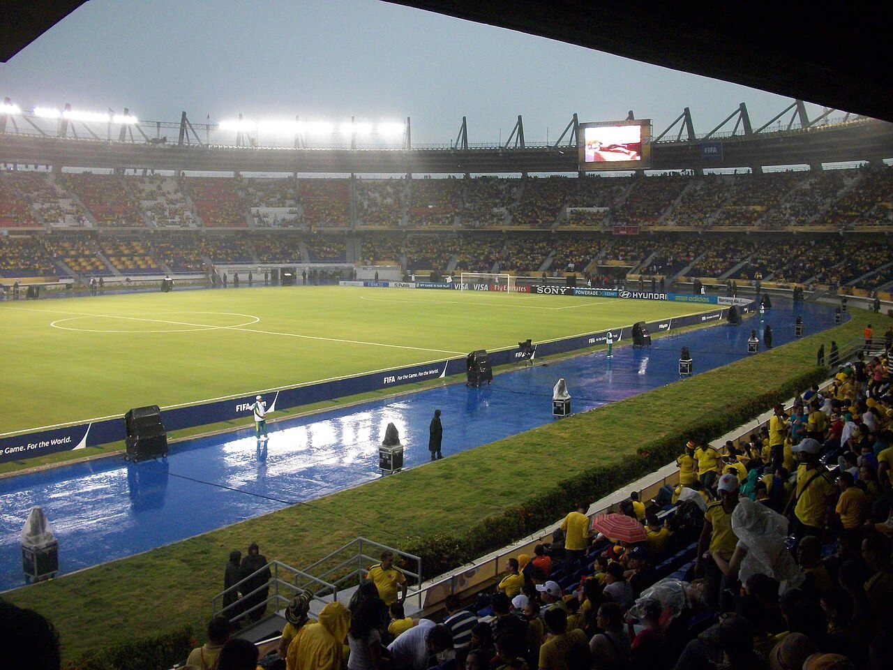 Rain falls on the pitch of Barranquilla's Estadio Metropolitano Roberto Meléndez as fans in yellow fill the stands